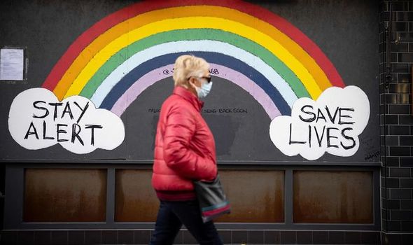 A pedestrian walks past coronavirus art
